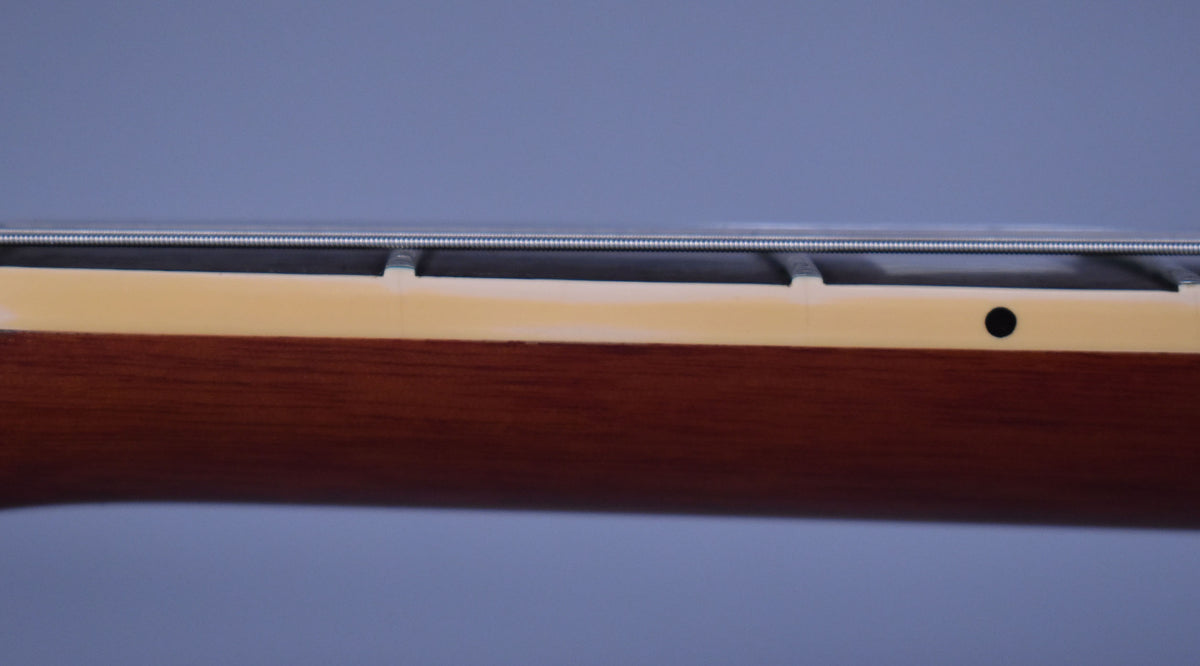 Close-up of the guitar's neck from the side, showing the dark wood, cream binding, frets, and a black side dot marker.