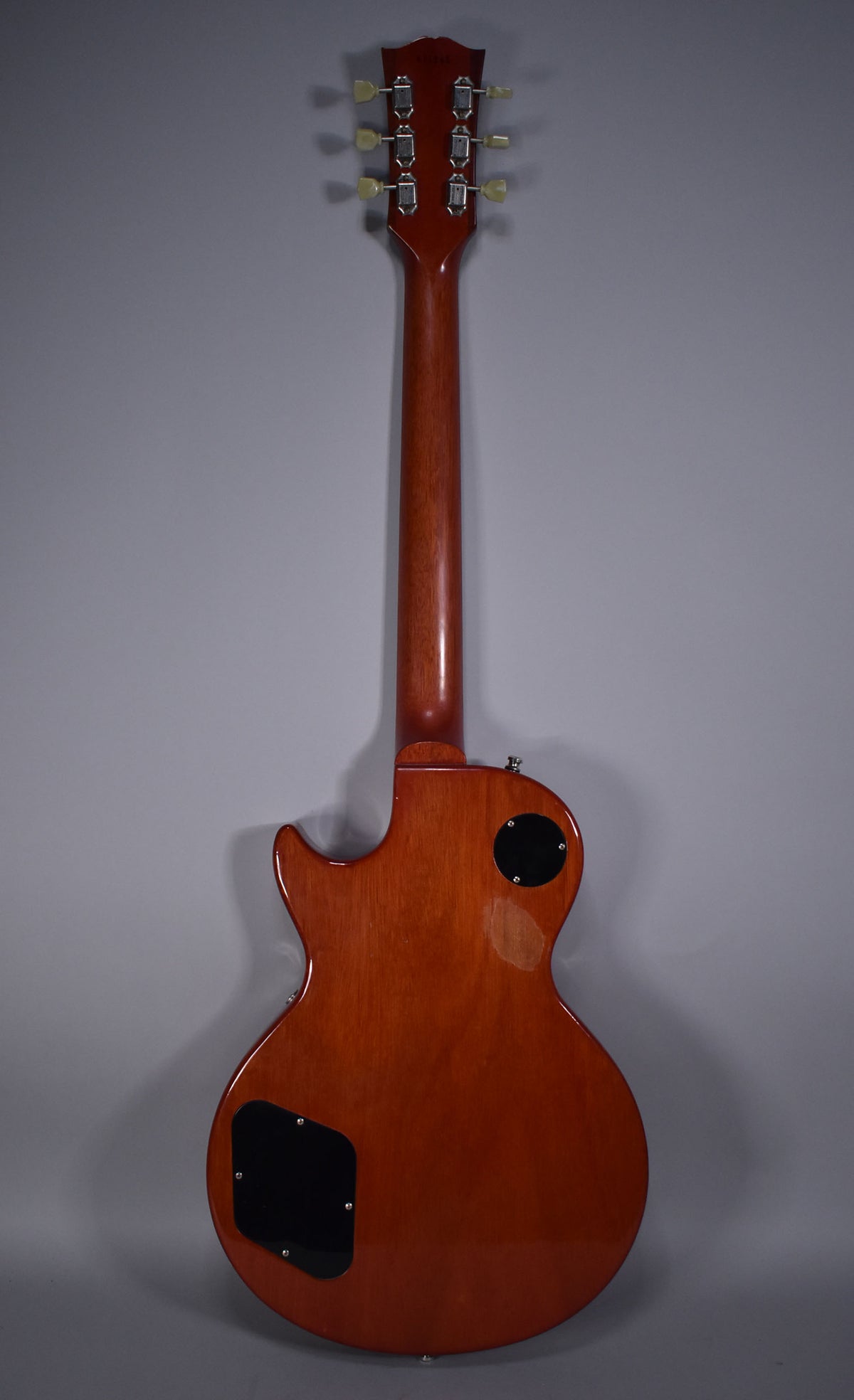 Full rear view of a cherry sunburst Les Paul, showing the headstock, neck, and body with two black control cavity covers.