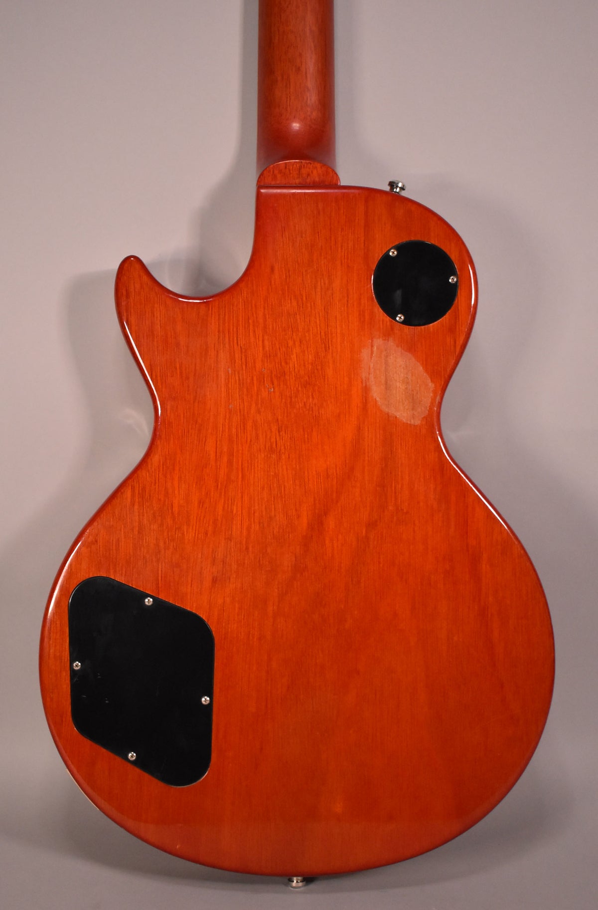 The guitar's cherry sunburst back and neck are visible, with two black control cavity covers and a strap button.