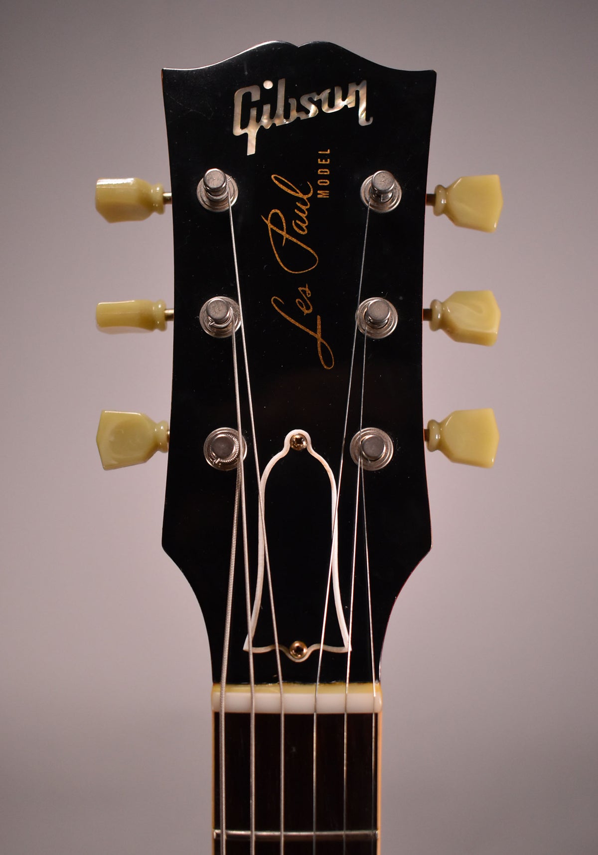 The black headstock, with cream tuning pegs and a bell-shaped truss rod cover, is framed from the nut upwards.