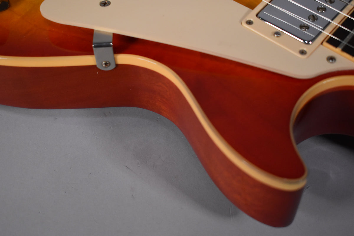 Close-up of the cherry sunburst body's lower bout and cutaway, showing the cream binding, pickguard, and neck pickup.