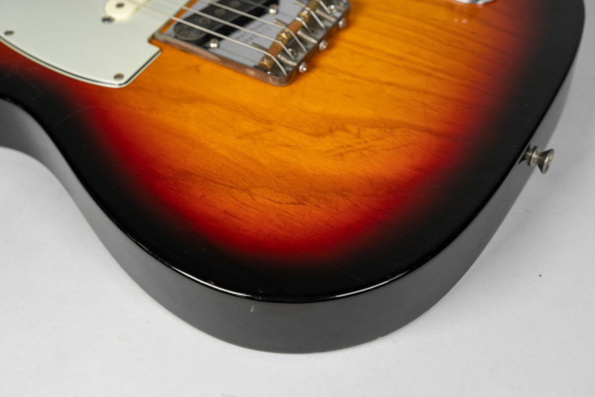 Close-up of the sunburst body, showing heavy relic wear, scratches, and finish checking on the top and side, with a chrome bridge.