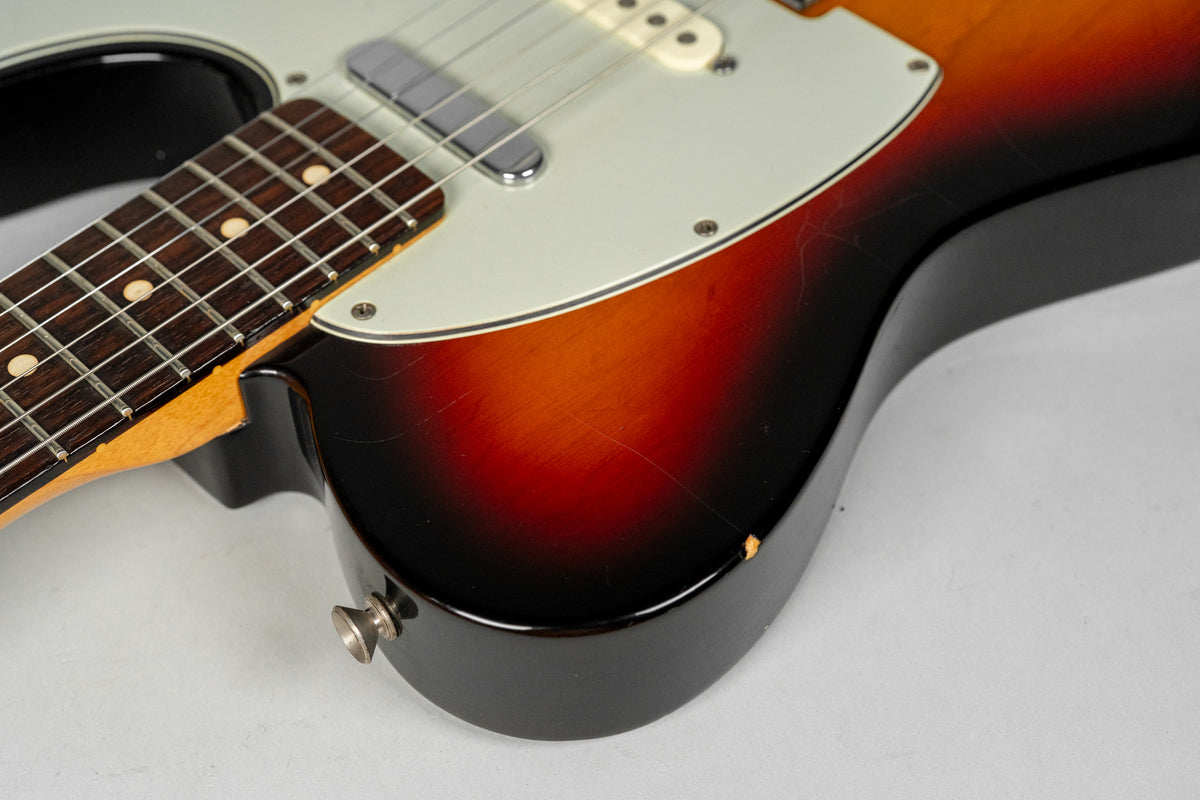Close-up of the sunburst body, showing finish checking, a chip near the strap button, and the lower fretboard with dot inlays.