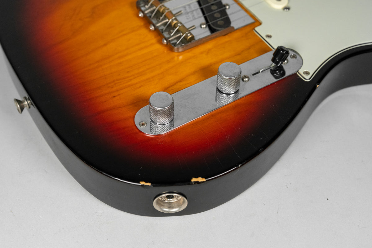 Close-up of the guitar's lower bout, showing the sunburst finish, control plate with two knurled knobs, and chipped paint near the output jack.
