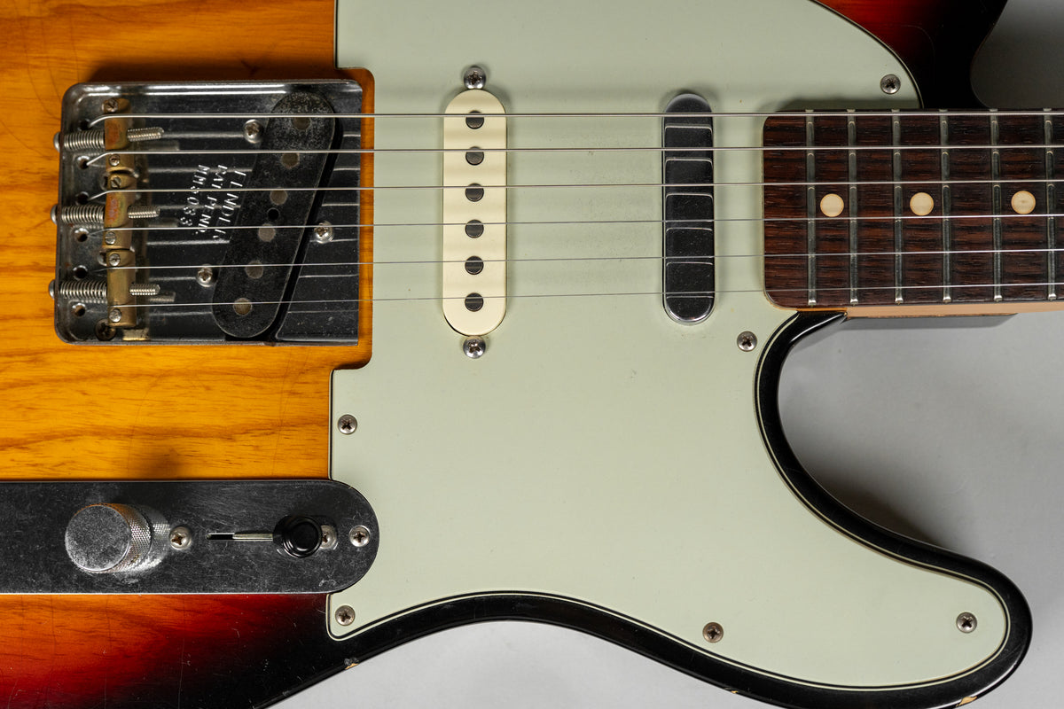 Close-up of the sunburst body and mint green pickguard, showing the bridge, middle single-coil, neck humbucker, and control plate.