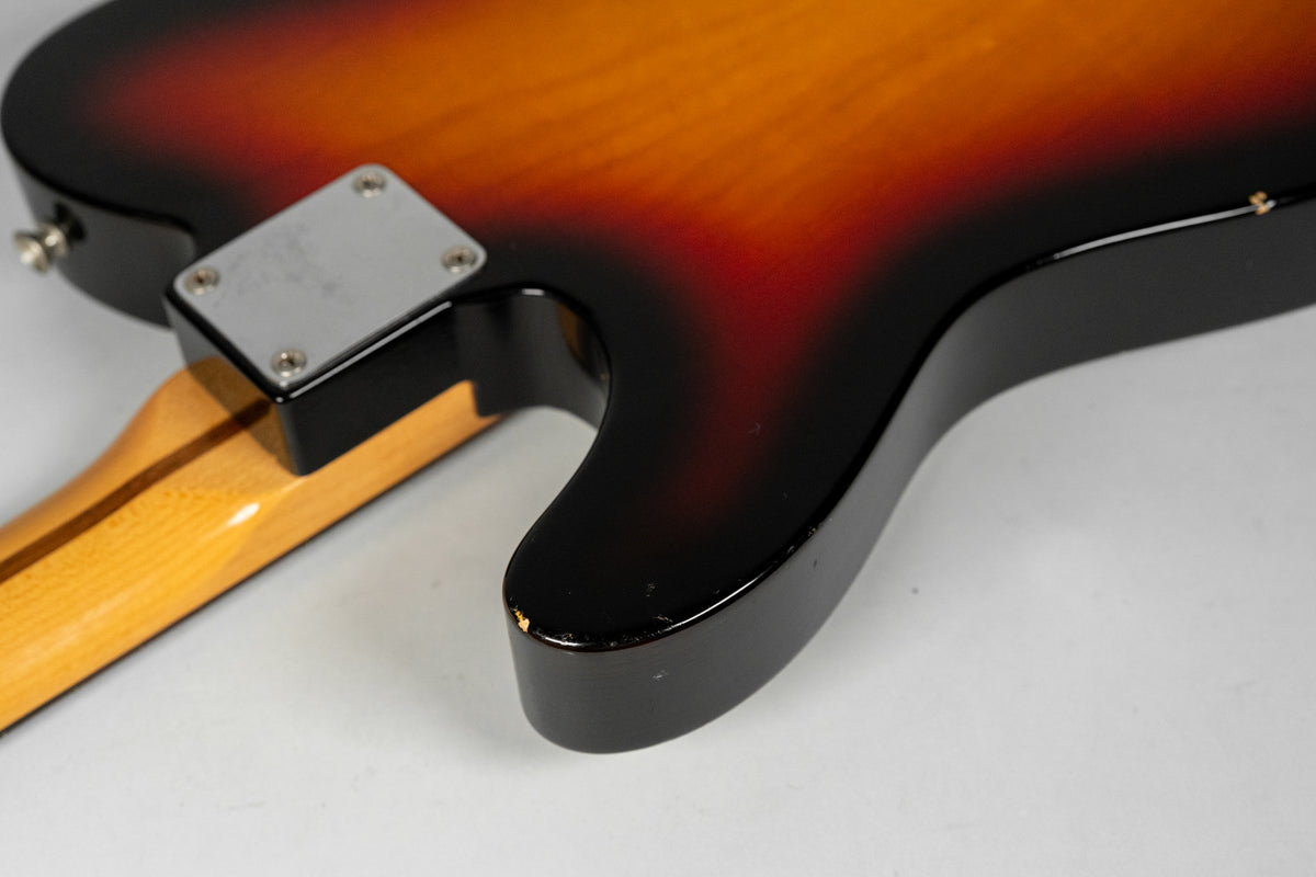 Close-up of the sunburst body and neck joint, showing a chrome neck plate and a chip in the finish on the lower horn.