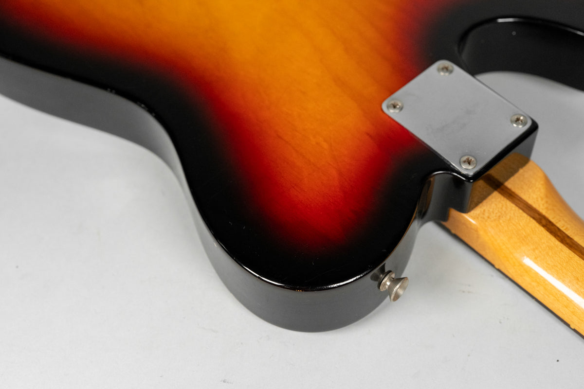 The guitar's sunburst body, showing wear and checking, curves to the input jack and a chrome neck plate on the light maple neck.