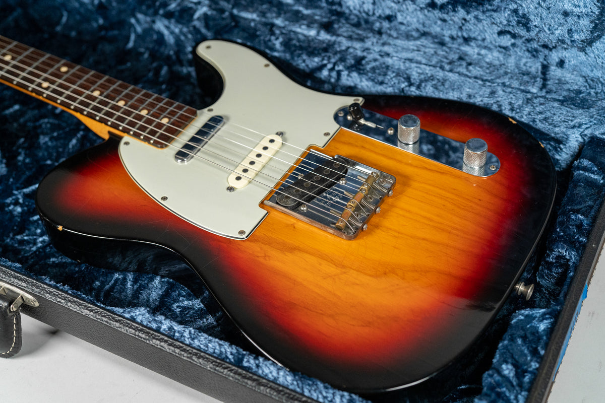 A sunburst Telecaster with a white pickguard and two chrome knobs, showing heavy relic wear on the lower bout and headstock.