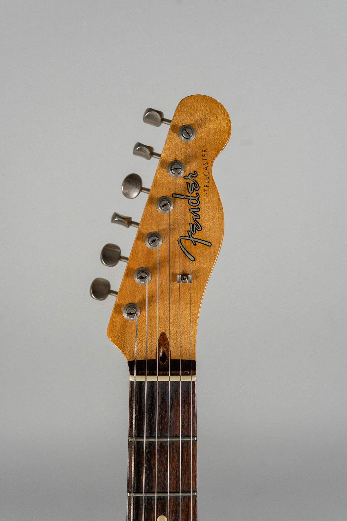 The headstock and upper fretboard of a relic'd Telecaster, showing six aged tuners, a dark rosewood fretboard, and light wear.