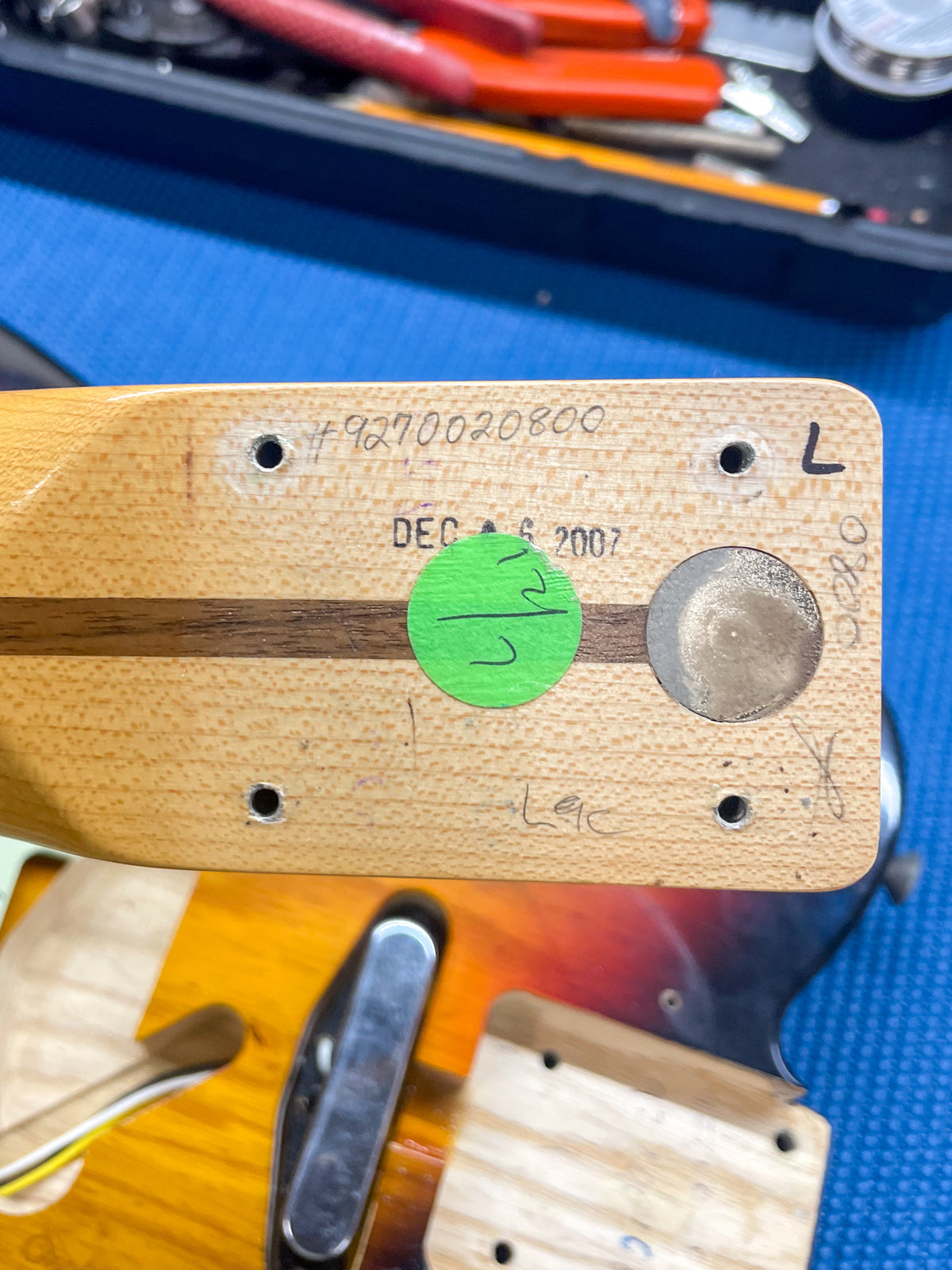 The guitar neck heel and body pocket are shown, revealing a light wood neck with a dark stripe and a sunburst body.
