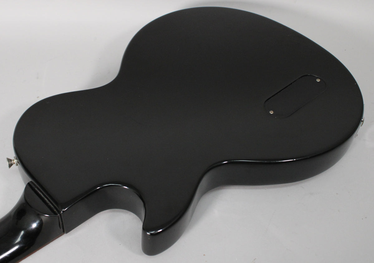 The back of the ebony guitar shows a matte finish with a glossy neck joint and a rectangular control cavity cover.