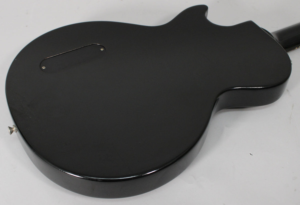 The back of an ebony Les Paul Jr. shows a matte finish with a glossy edge, a control cavity cover, and light wear.