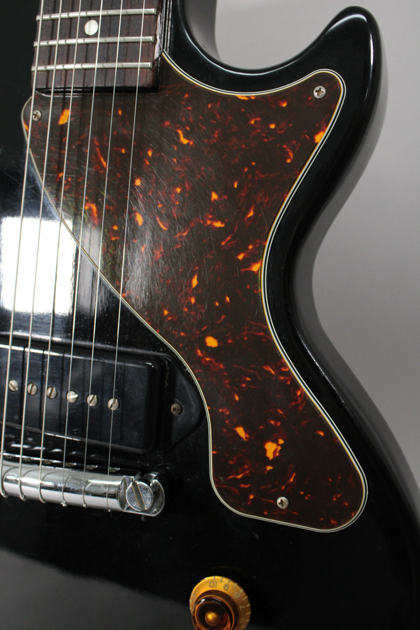 Close-up of the ebony body, showing the tortoiseshell pickguard with visible scratches, P90 pickup, and a gold volume knob.