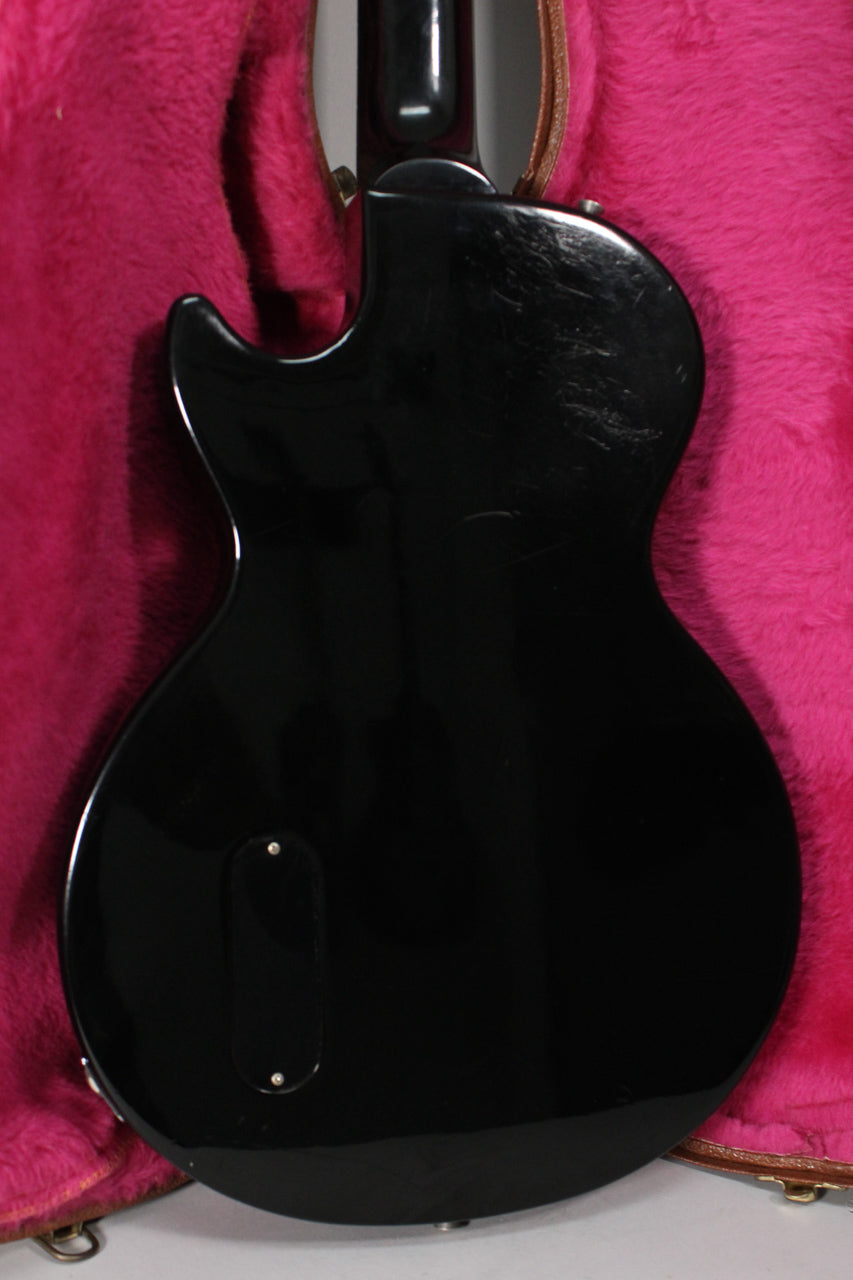 Rear view of the glossy black Les Paul Jr. body, showing light scratches on the upper bout and a control cavity cover.