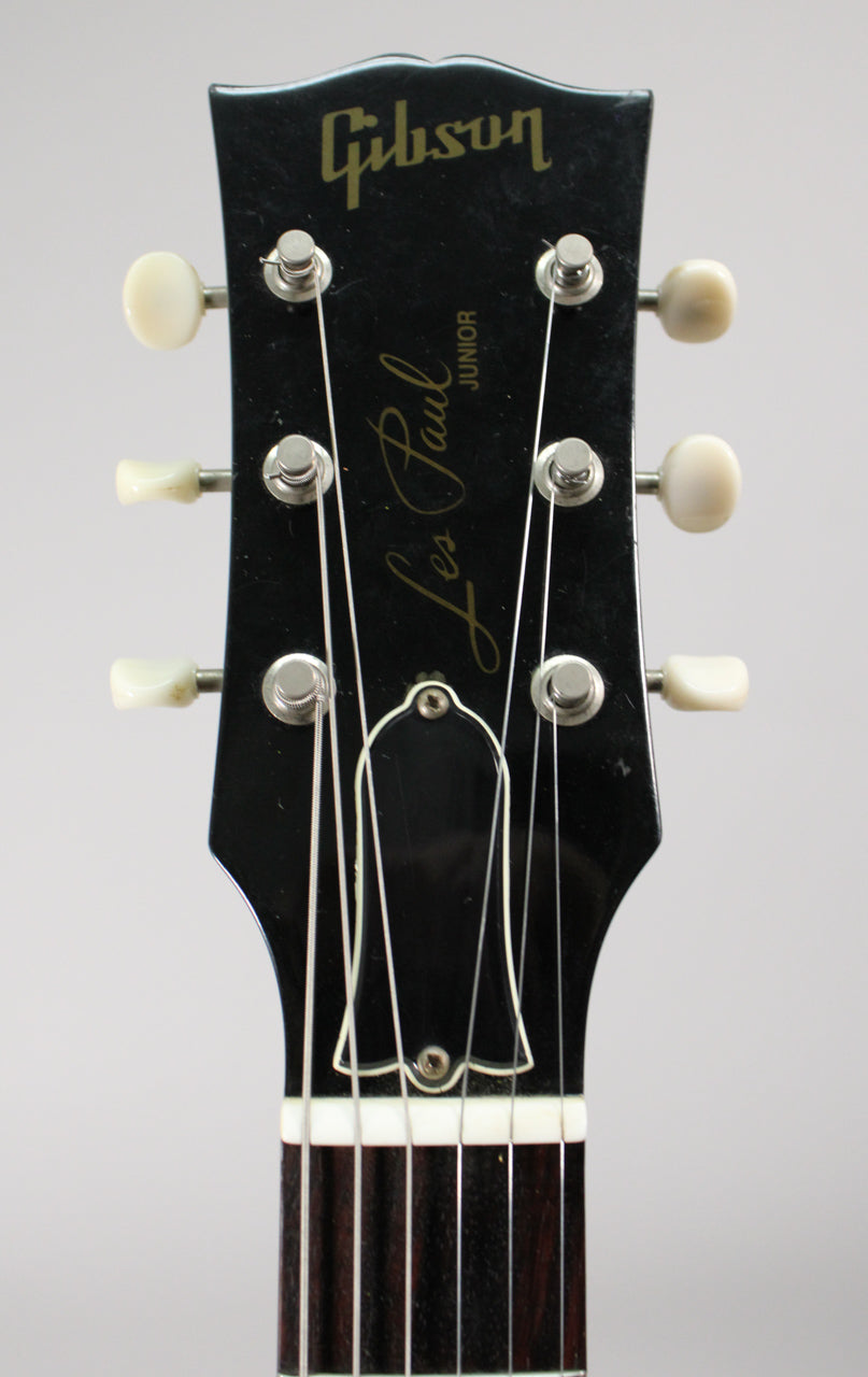 The ebony headstock, with six cream tuners and a black truss rod cover, shows light wear and dust.