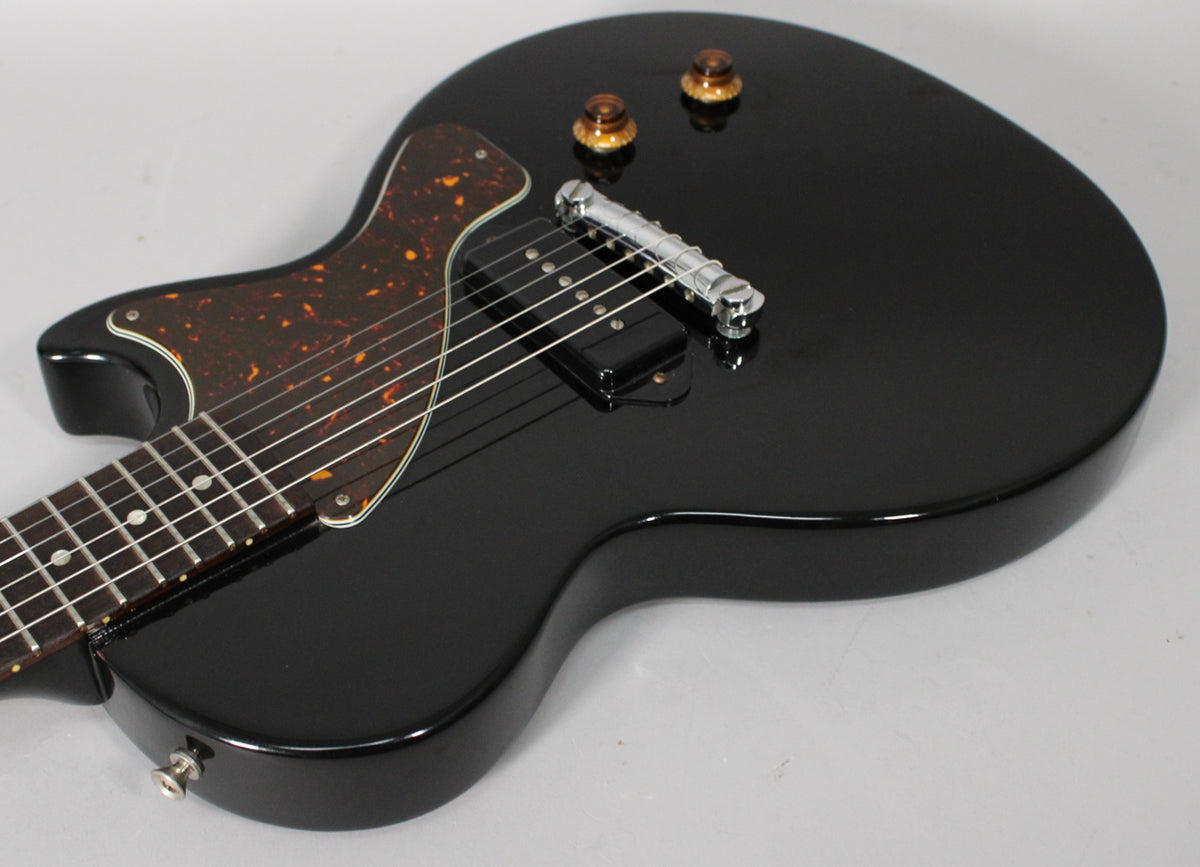 Ebony Les Paul Jr. body, angled from the lower bout, showing a tortoiseshell pickguard, single P90 pickup, and two amber knobs.