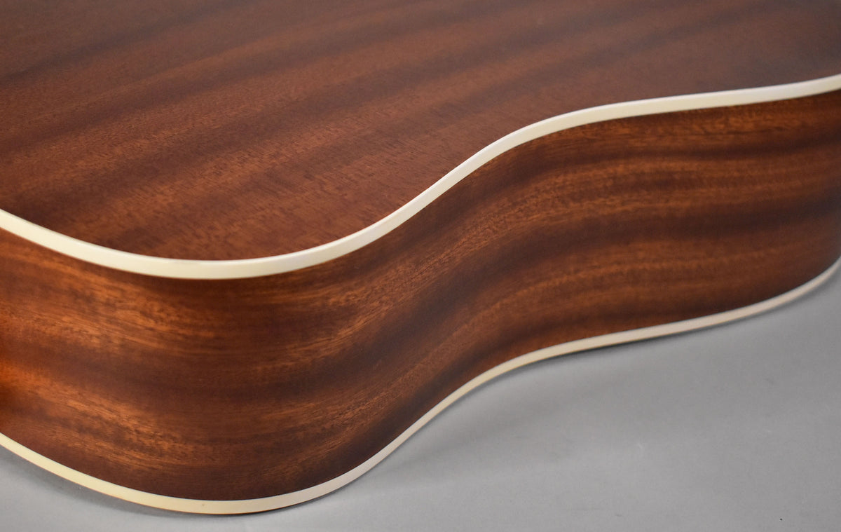Close-up of the guitar's lower bout, showing the dark reddish-brown wood grain of the body and the light binding along the edge.