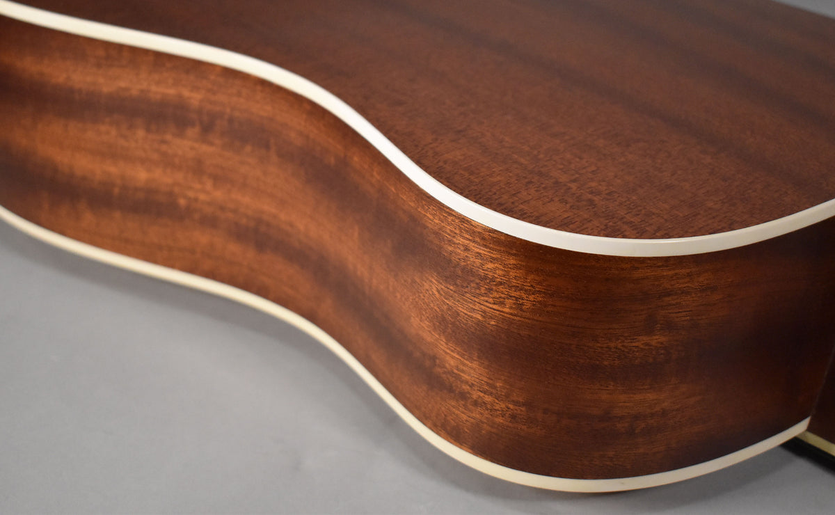 Close-up of the guitar's lower bout, showing the natural wood grain, matte finish, and cream binding along the edges.