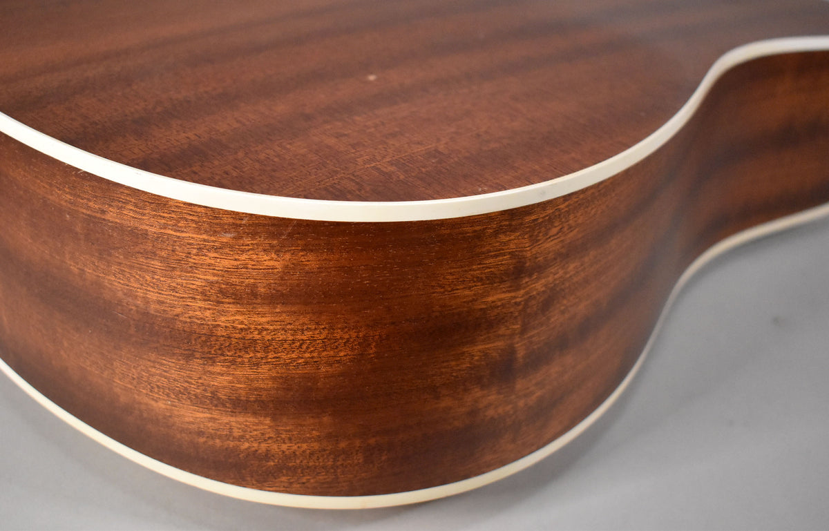 Close-up of the guitar's upper bout, showing the dark brown wood grain, natural finish, and cream binding along the edges.