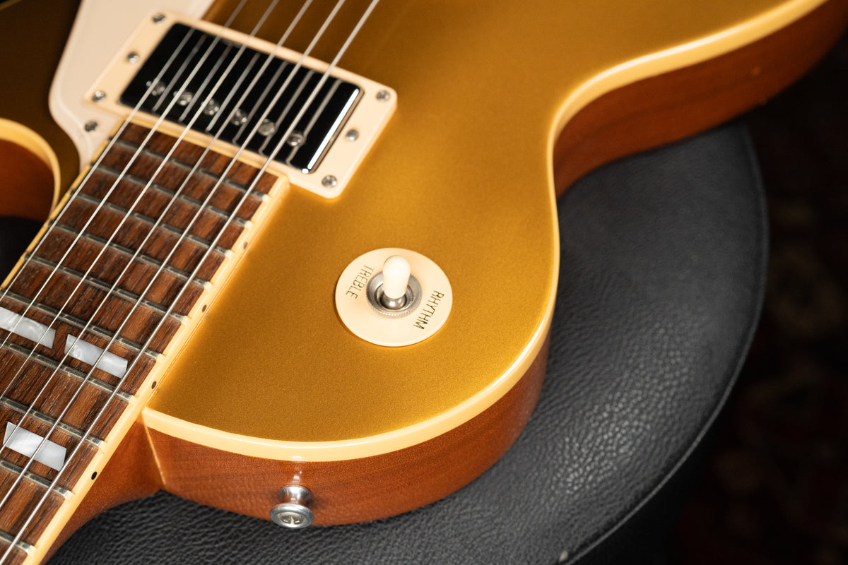 Close-up of the goldtop body, showing the neck pickup, cream switch plate with "Rhythm" and "Treble" text, and the lower bout.