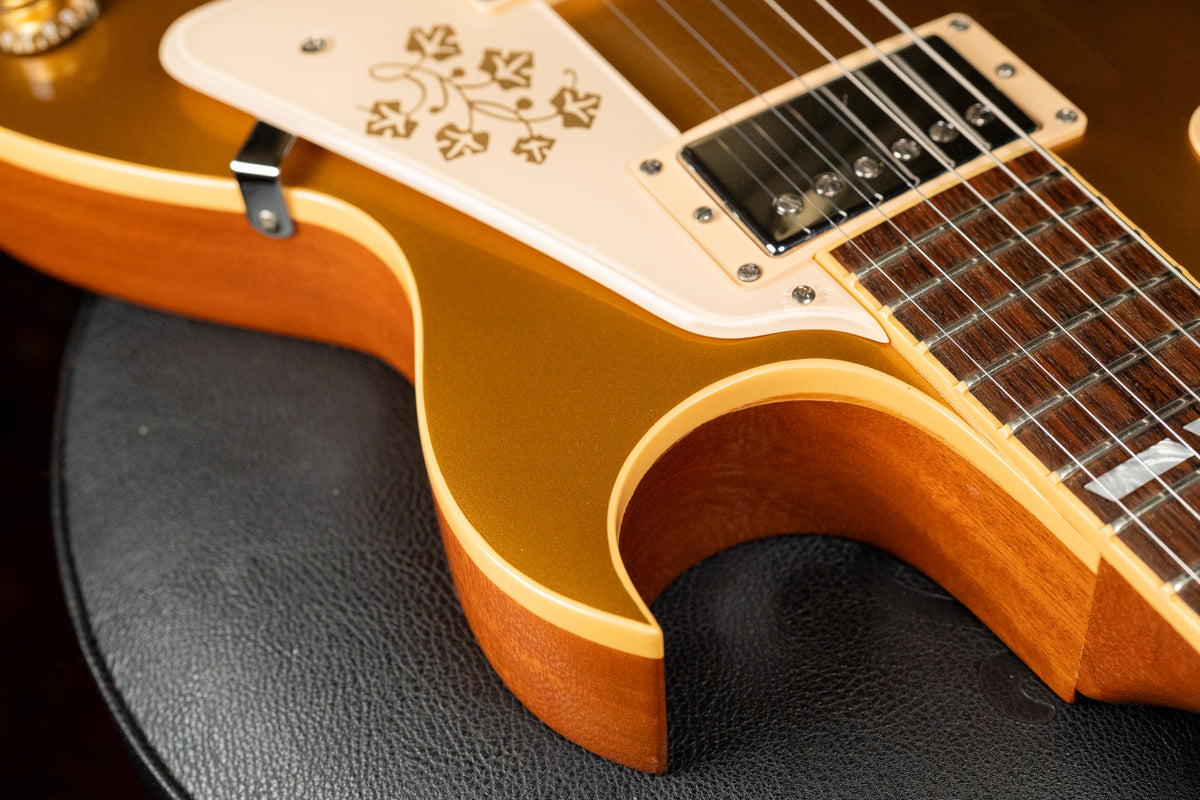 Close-up of the goldtop body and cutaway, showing the cream pickguard with gold floral design and a humbucker pickup.