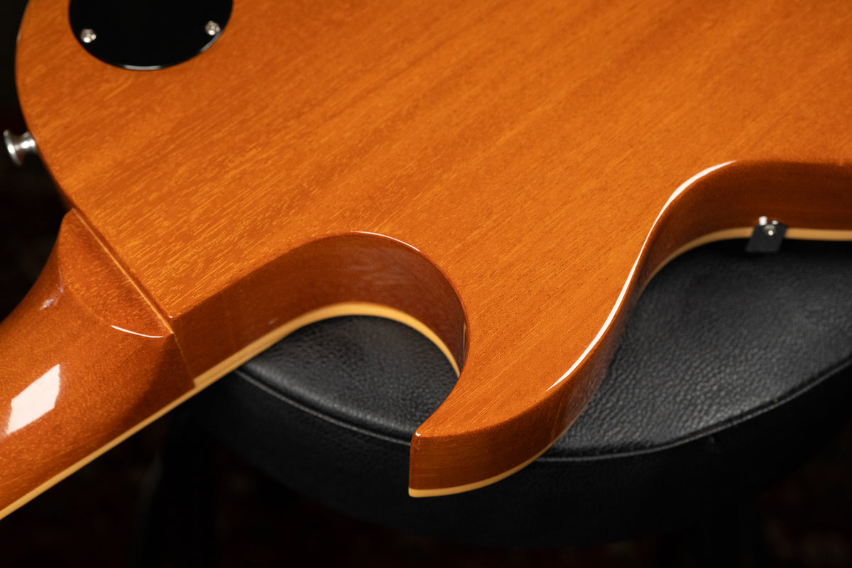 Close-up of the guitar's honey-colored back, showing the neck joint and cutaway, with light reflections on the glossy finish.