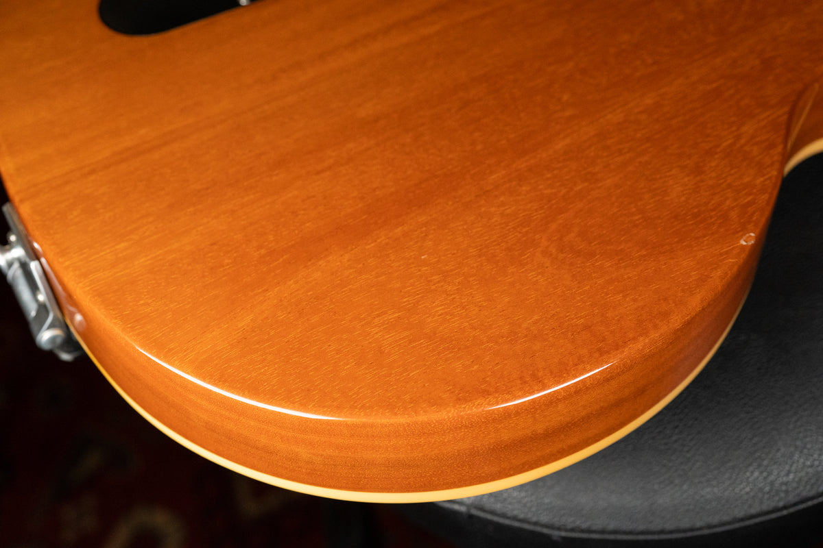 Close-up of the guitar's lower bout, showing the glossy goldtop finish with wood grain, cream binding, and a small chip on the edge.