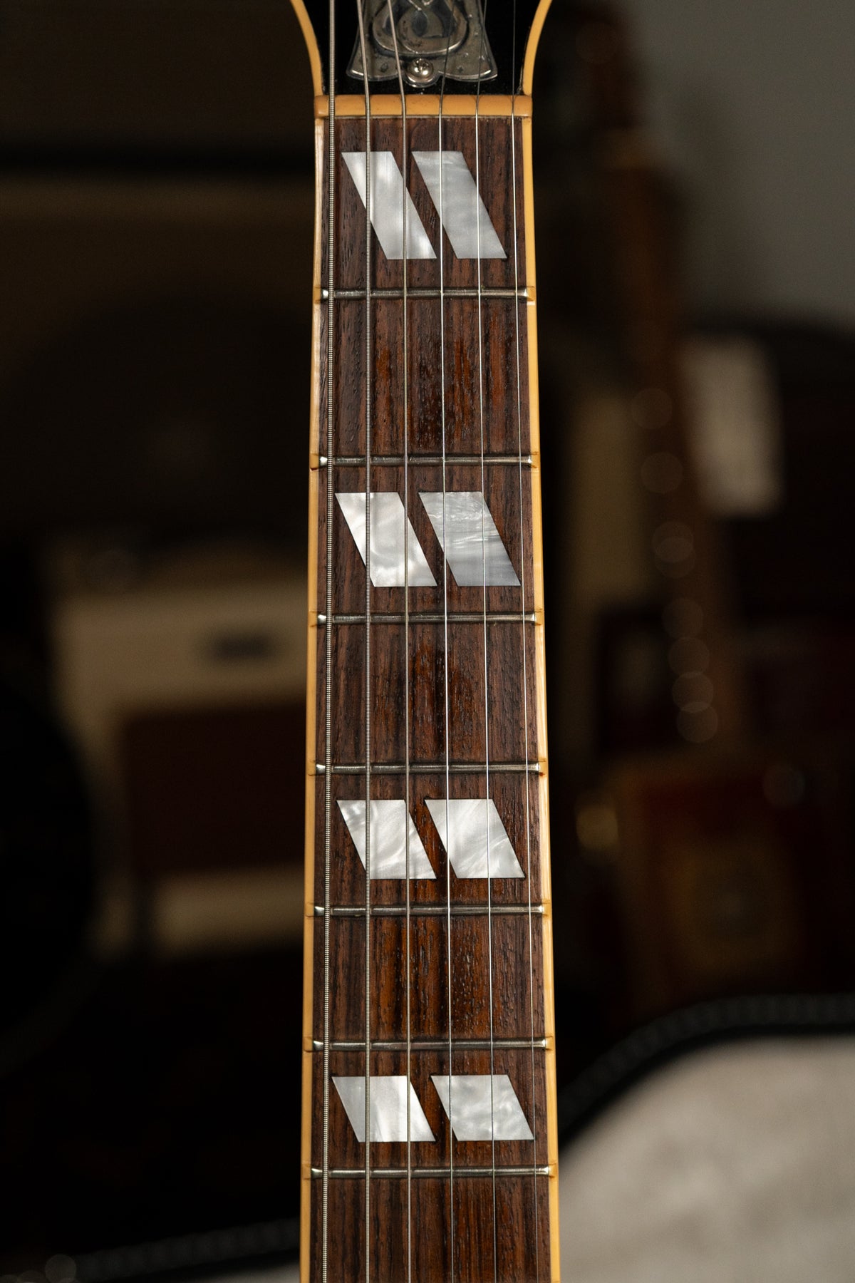 Close-up of the dark rosewood fretboard with trapezoid mother-of-pearl inlays, showing frets 1-7 and the top of the headstock.