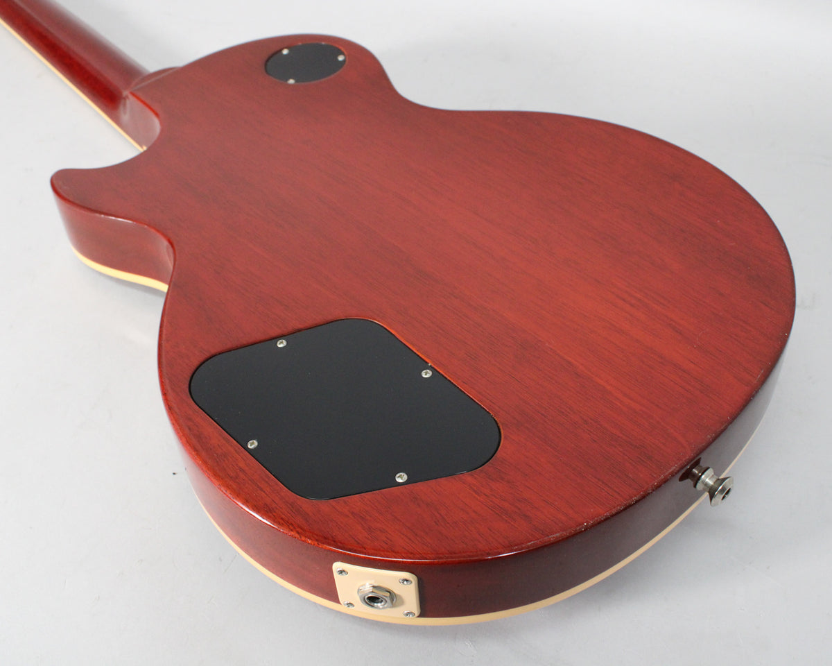 The back of a rootbeer-finished electric guitar, showing the control cavity and output jack, with some light wear on the body.