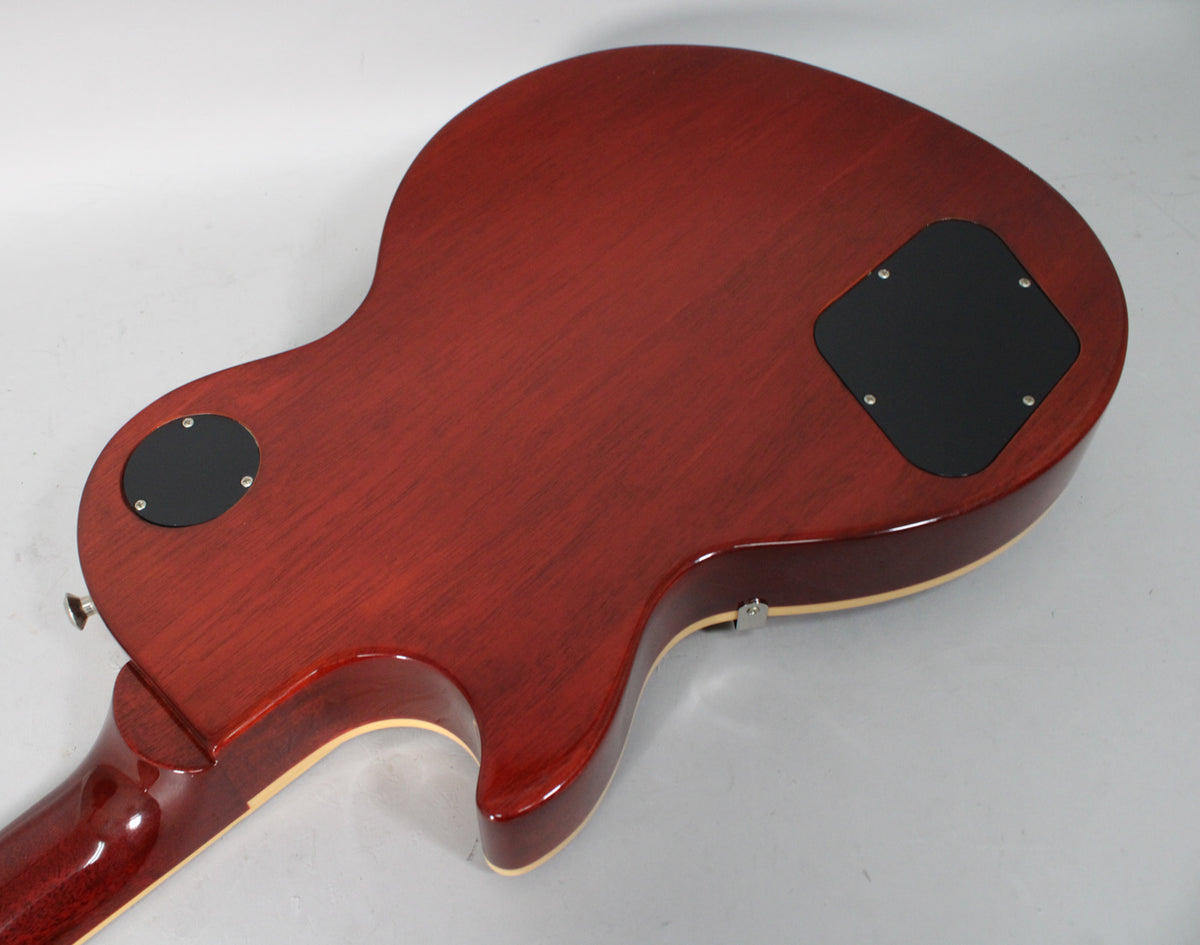 The guitar's rootbeer-stained mahogany back is angled from the neck to the lower bout, showing two black control cavity covers.