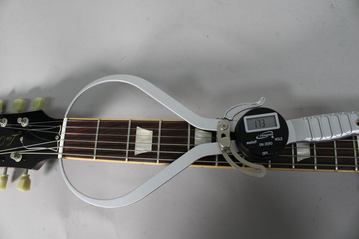Close-up of the guitar's headstock and upper fretboard, with a digital caliper measuring the nut width at 1.73 inches.