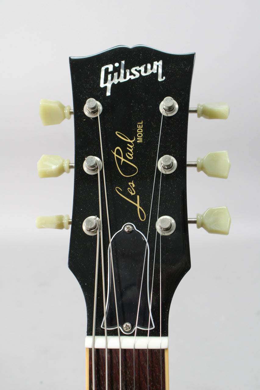 Close-up of the black headstock with cream tuning pegs, showing the top of the fretboard and strings.