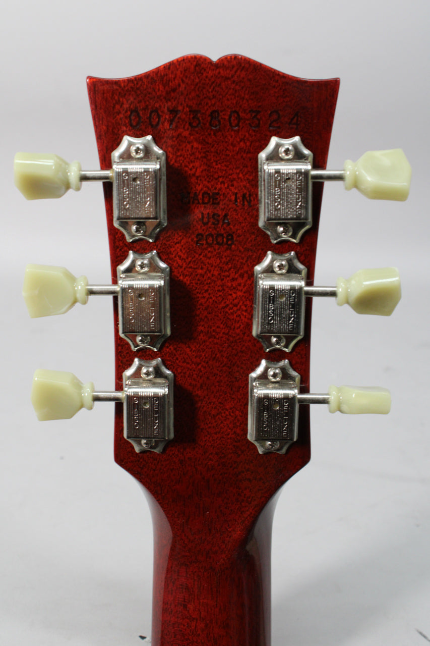 The back of a reddish-brown guitar headstock with six chrome tuners and cream-colored buttons, showing light wear.