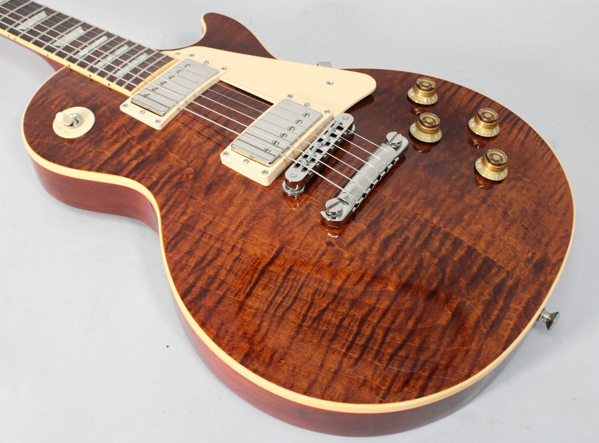 The rootbeer-finished Les Paul body is angled from the neck, showing the flamed maple top, cream binding, and gold top hat knobs.