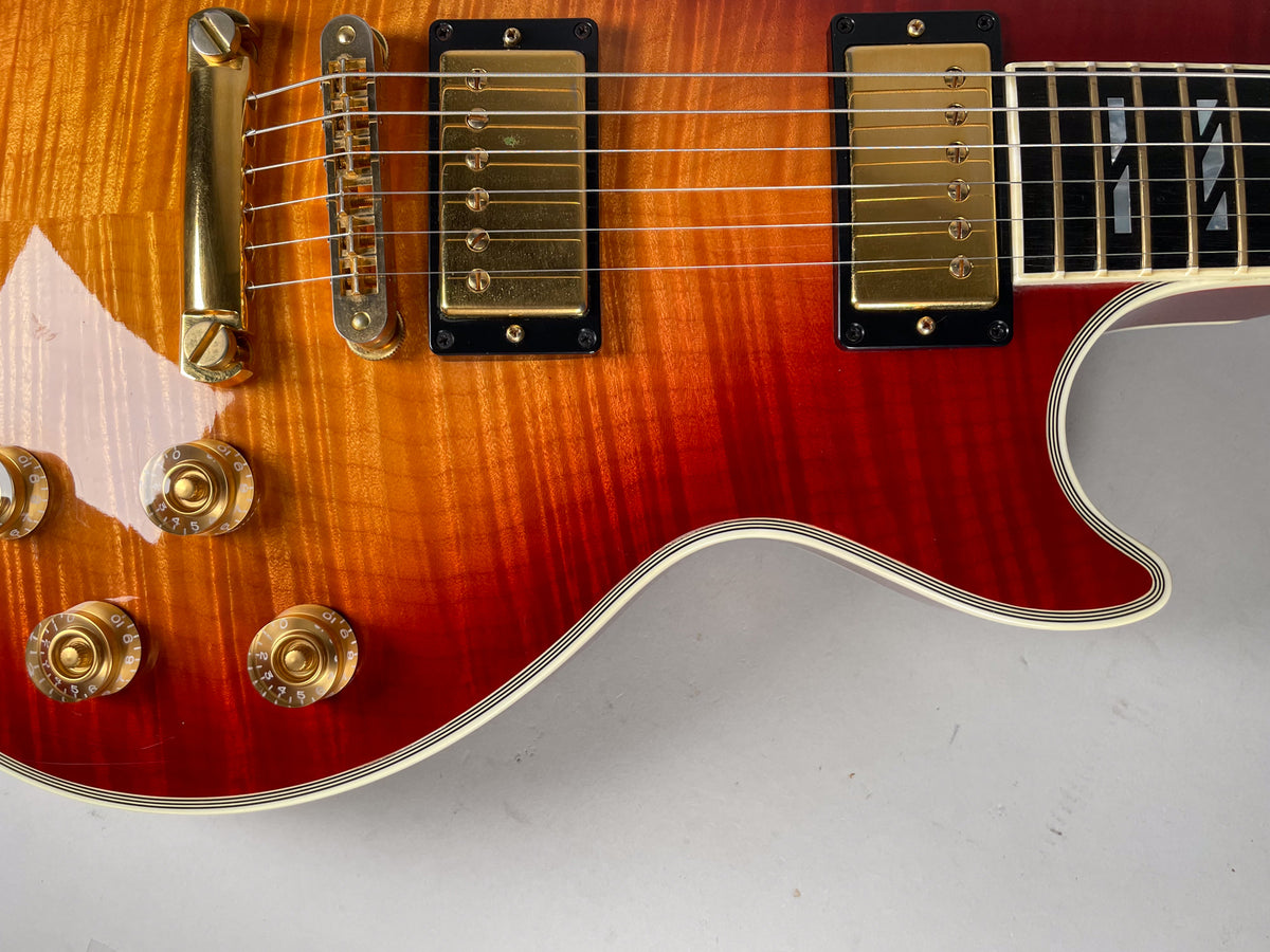 Close-up of the cherry sunburst body, showing gold hardware, four gold control knobs, and multi-ply binding.