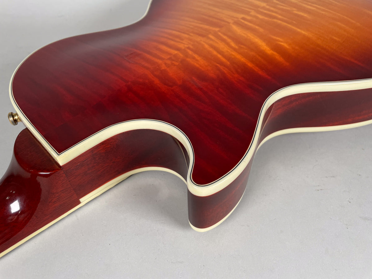 Close-up of the guitar's cherry sunburst body, showing the flame maple top, cream binding, and neck joint from an overhead angle.