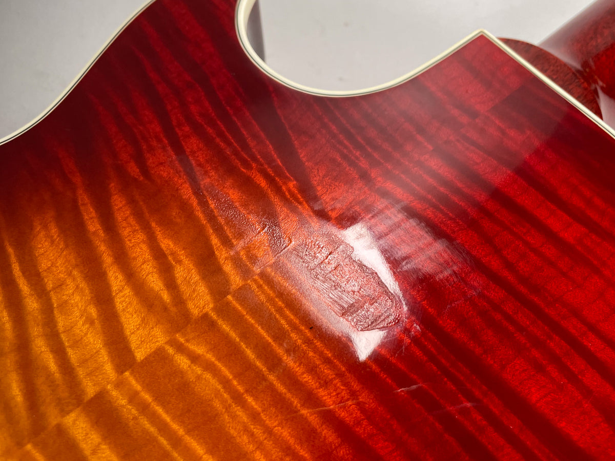Close-up of the cherry sunburst body, showing a large, deep gouge in the finish near the lower bout.