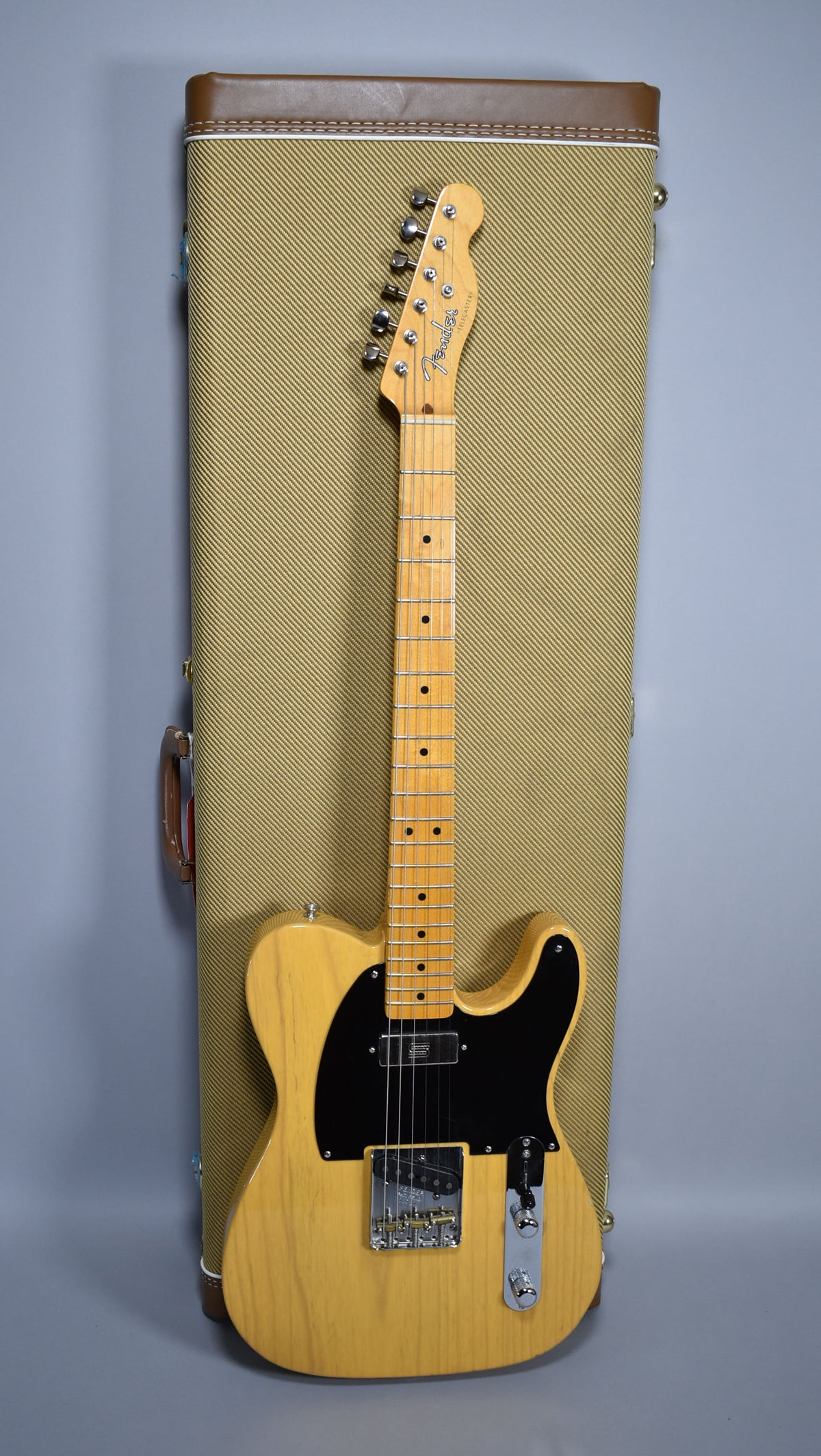 Full-length view of a blonde Telecaster with a black pickguard and maple neck, resting against a tweed hard case.