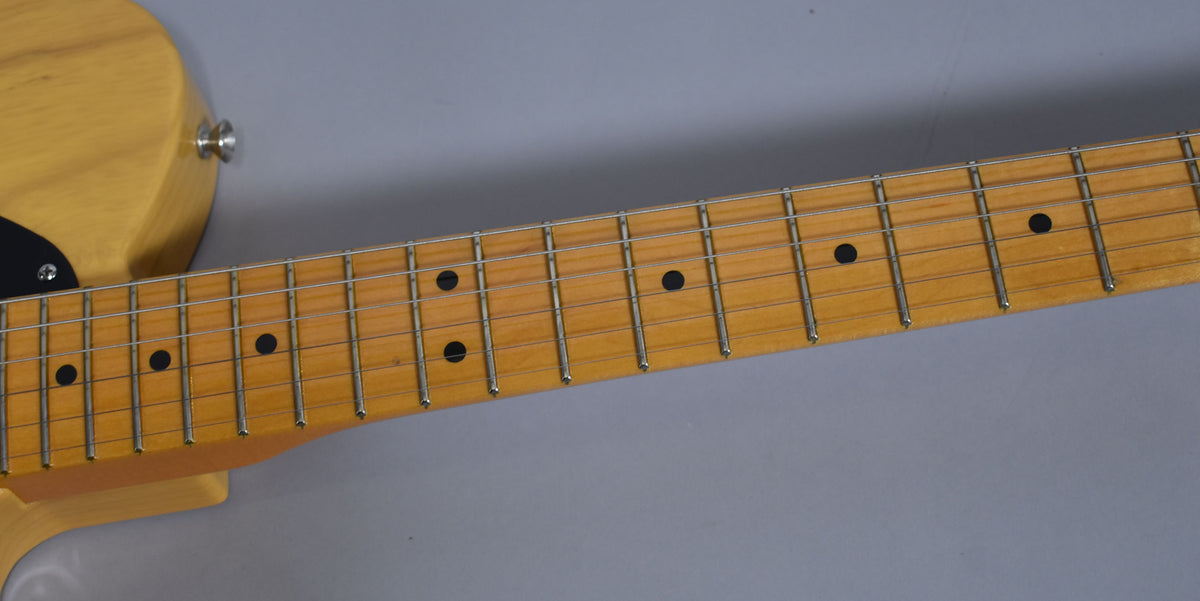 Close-up of the guitar's maple fretboard with black dot inlays and chrome frets, showing light wear on the frets and wood.