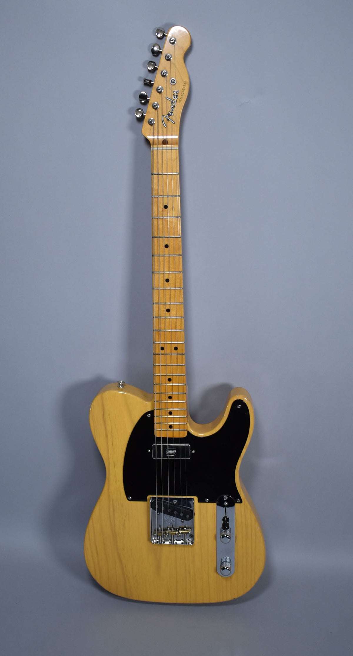 Full front view of a blonde Telecaster with a black pickguard, maple fretboard, and chrome hardware, showing light body wear.