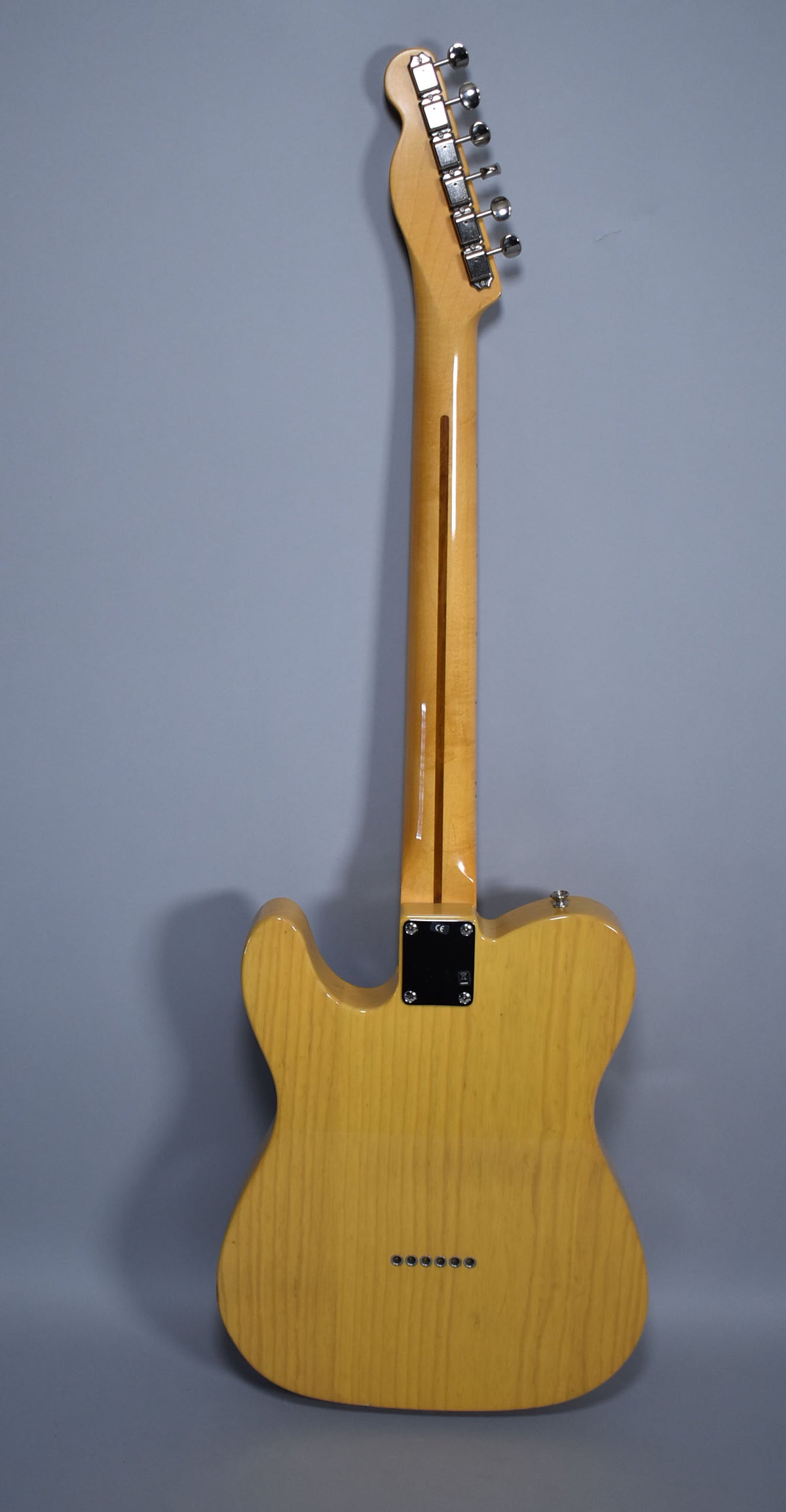 Full rear view of a blonde Telecaster with a maple neck, chrome tuners, and six string-through-body ferrules.