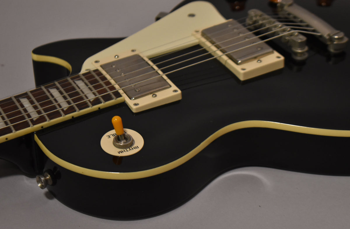 Close-up of the glossy black body, showing cream binding, two humbuckers, and an amber-tipped pickup selector switch.