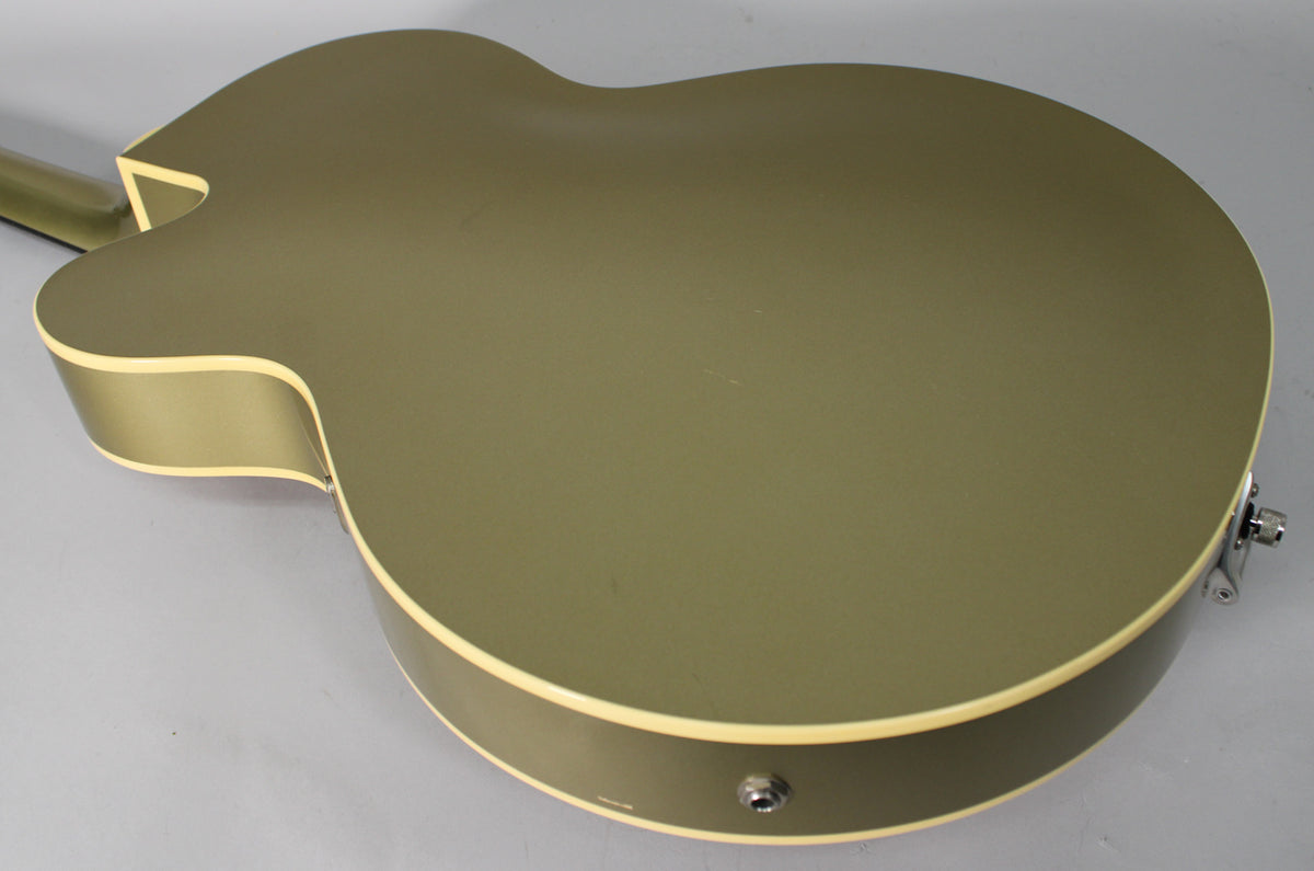 The back of a tan hollow-body electric guitar with cream binding, showing the input jack and strap button.