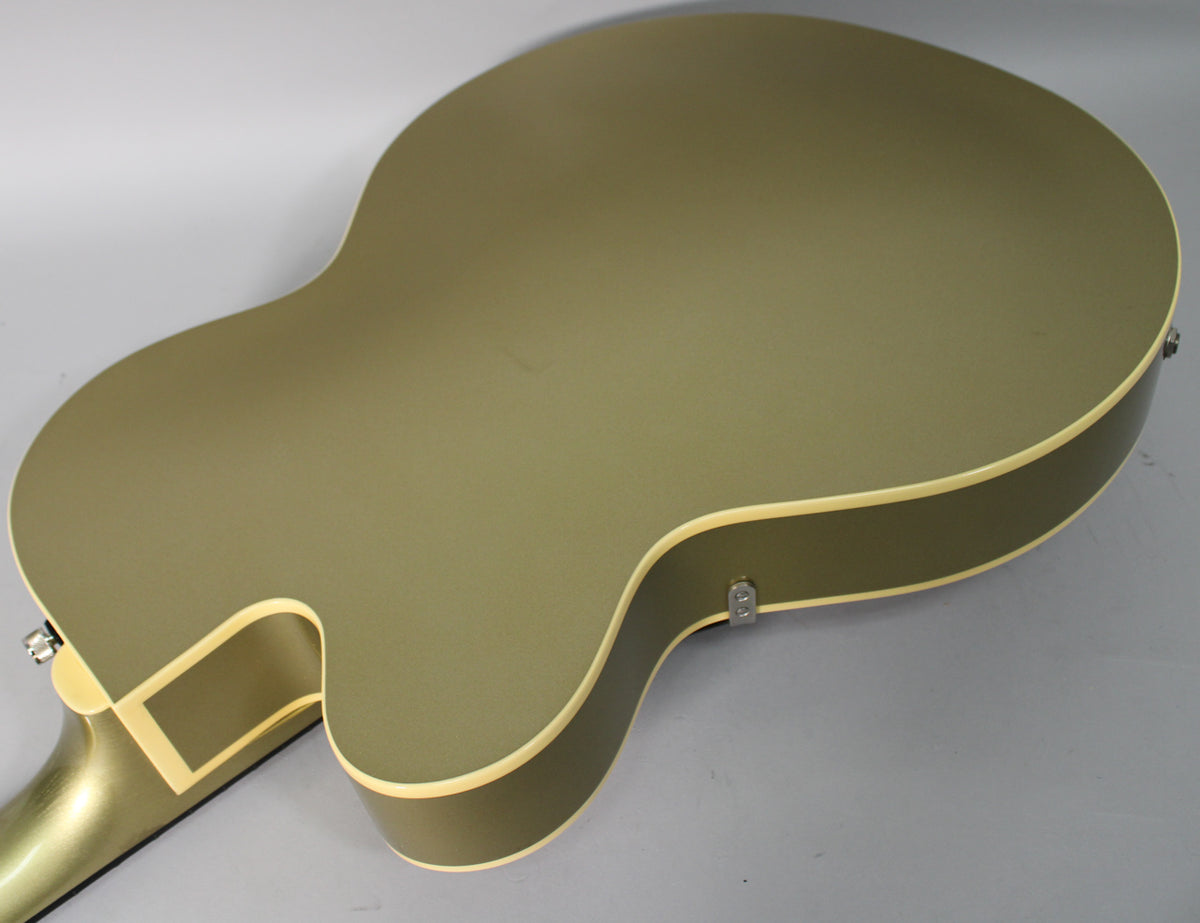 The back of the tan hollow body electric guitar, showing the lower bout and cutaway, with cream binding and a strap button.