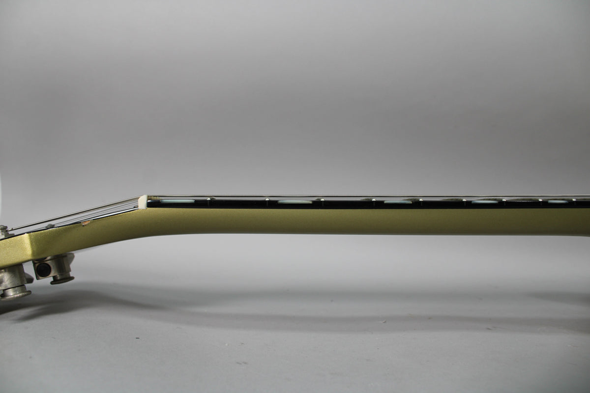 Side view of the guitar's tan neck and headstock, showing the fretboard with block inlays and the tuning pegs.