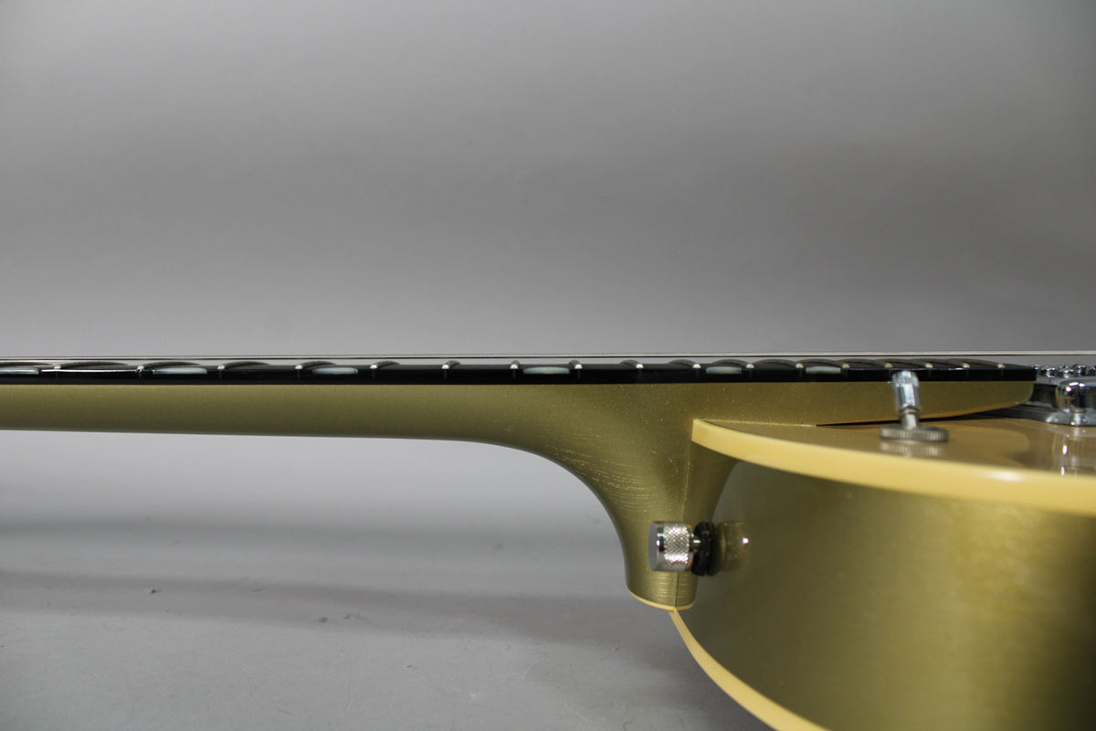The guitar's tan body and neck are viewed from the side, showing the fretboard and a chrome strap button near the neck joint.