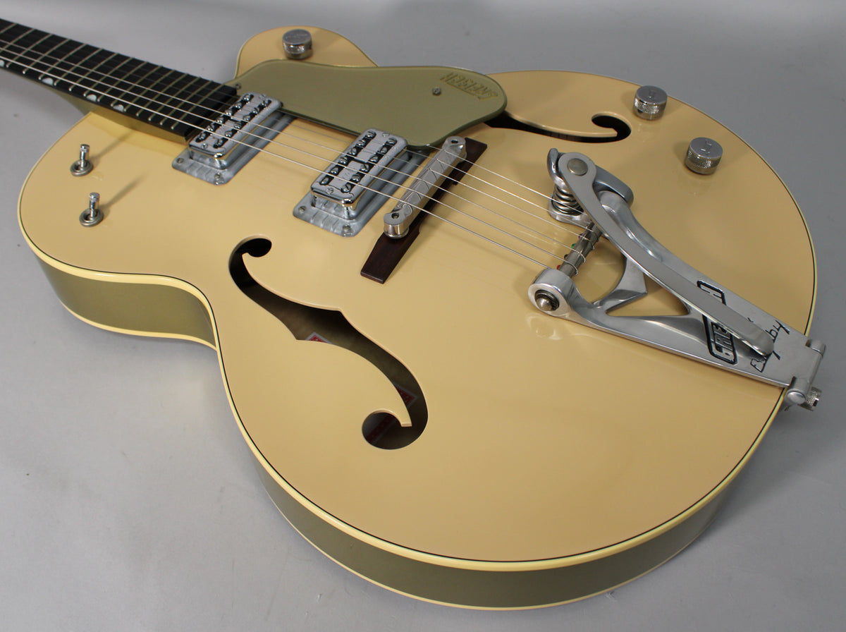 Tan hollow-body electric guitar, angled from the neck to the Bigsby vibrato, showing two f-holes and chrome hardware.