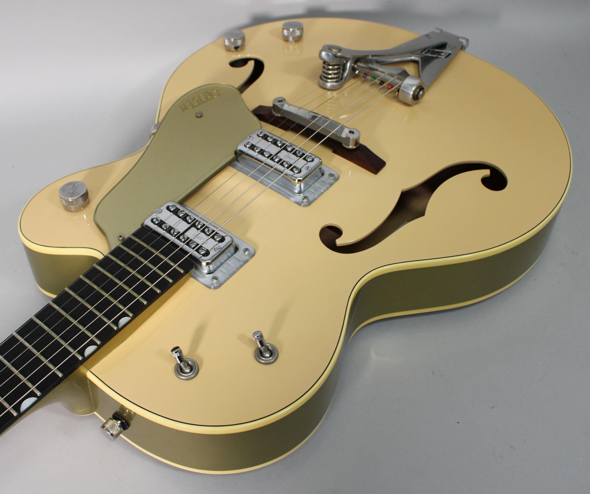 Tan hollow-body electric guitar, angled from the lower bout, showing two f-holes, a Bigsby vibrato, and two humbucker pickups.
