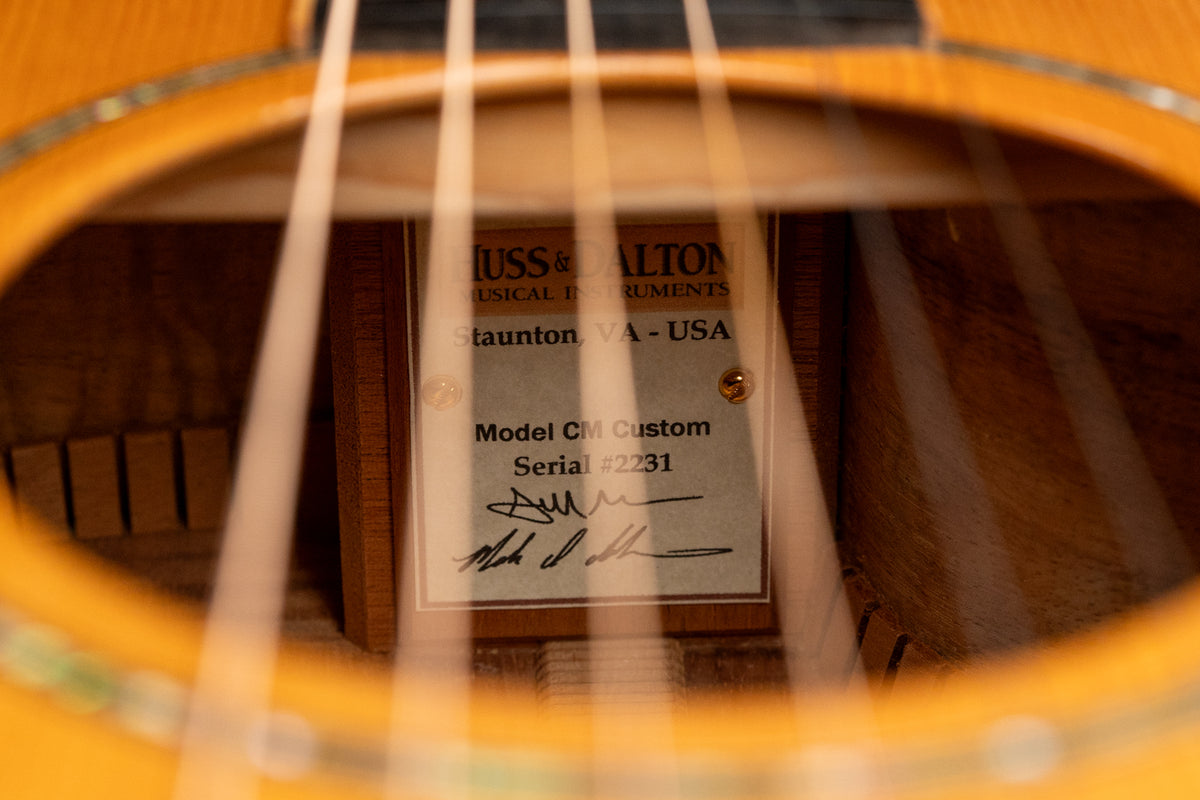 A close-up of the guitar's soundhole, revealing the interior label with "Model CM Custom" and "Serial #2231" printed on it.