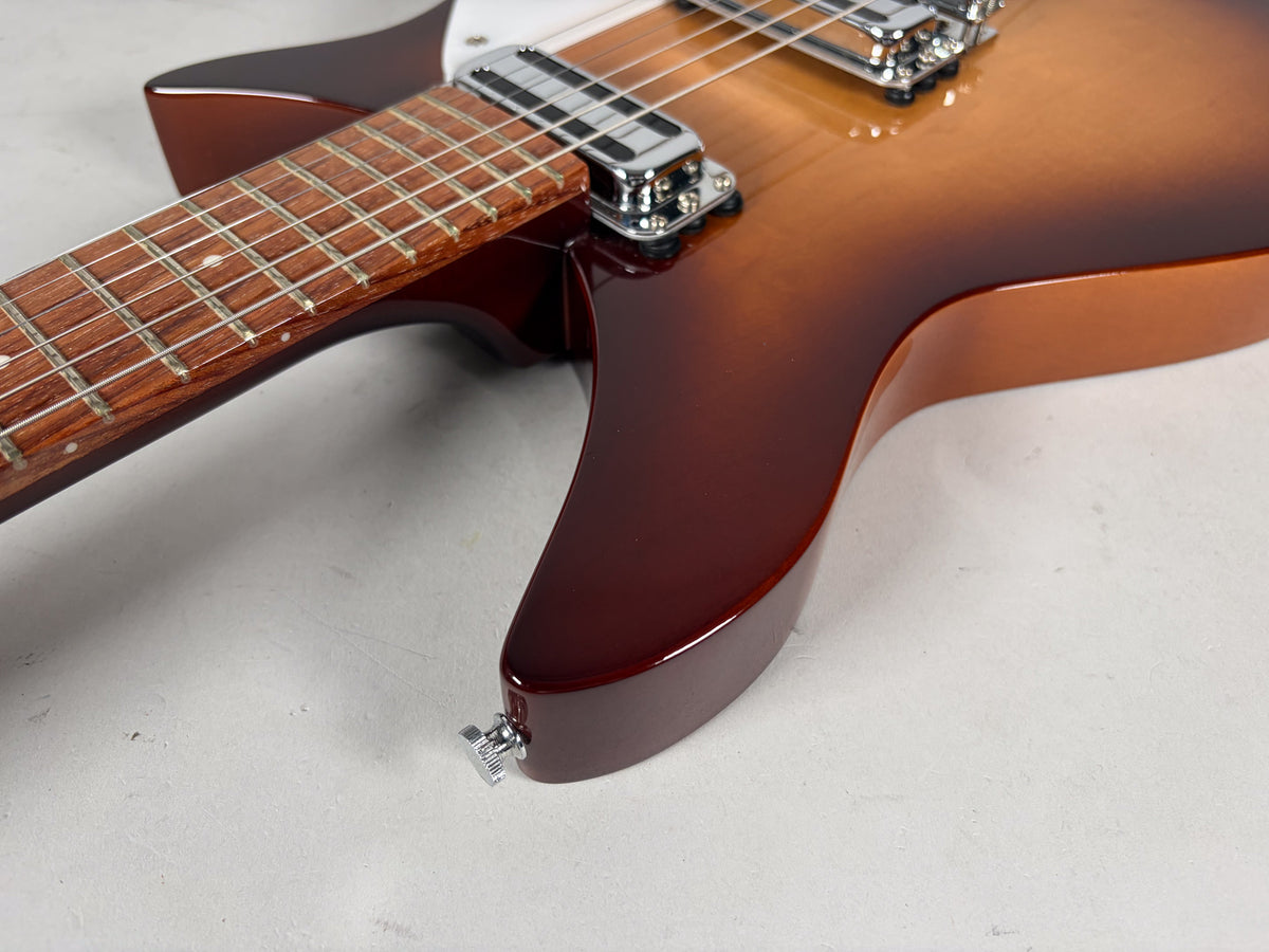 The guitar's Montezuma Brown finish transitions from dark brown to amber, with a rosewood fretboard and chrome pickups visible.